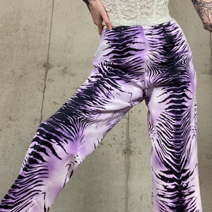 May include: Purple and black zebra print pants. The pants have a wide leg and a high waist.