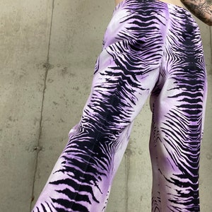 May include: Purple and black zebra print pants. The pants are wide-legged and have a high waist.