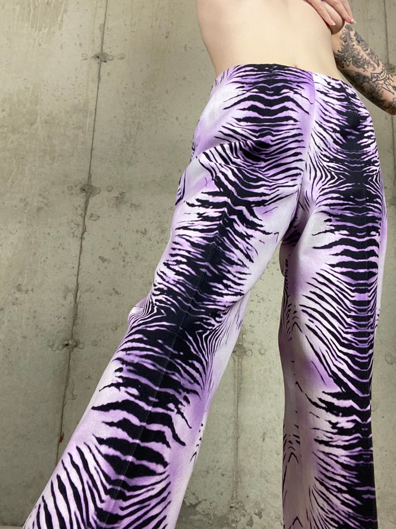 May include: Purple and black zebra print pants. The pants are wide-legged and have a high waist.
