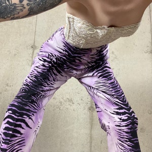 May include: A person wearing a white lace strapless top and purple and black zebra print pants.