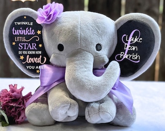 May include: A gray plush elephant with a purple bow and flower. The elephant's ear has the name "Layke Dean Barrish" embroidered on it. The other ear has the text "Twinkle twinkle little star, do you know how loved you are?"