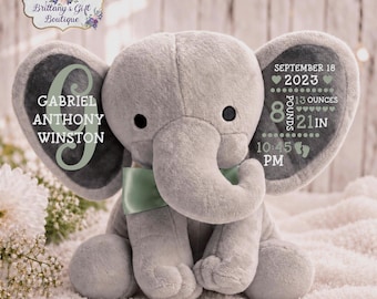 Puede incluir: Un peluche de elefante gris con una pajarita verde salvia. La oreja izquierda muestra el nombre Gabriel Anthony Winston con una letra G grande. La oreja derecha contiene datos de nacimiento: 18 de septiembre de 2023, 3,99 kg, 53 cm y 22:45.