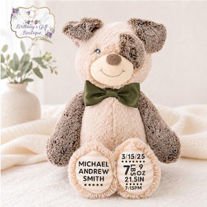 May include: A plush puppy toy with tan and dark brown fur, wearing a dark olive green satin bow tie. The puppy's feet are embroidered with the name Michael Andrew Smith, the date 3/15/25, the weight 7 lbs 9 oz, the length 21.5 in, and time 7:15 PM.