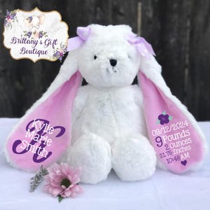 May include: White plush bunny with pink ears and a purple bow. The ears are embroidered with the name "Kylie Marie Smith" and the date "09/12/2024", weight "9 pounds 2 ounces", length "21.75 inches", and time "10:48 AM".