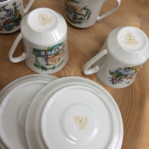 May include: Set of four white ceramic teacups with colorful illustrations of people fishing and sailing. The cups have gold lettering on the bottom that reads "Valenciennes & Sons, Ltd. England". The set also includes two white ceramic saucers with the same gold lettering on the bottom.
