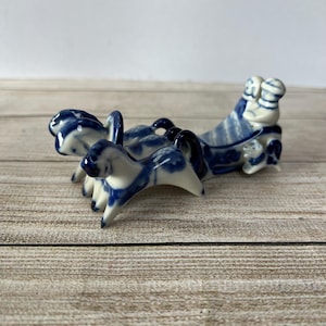 May include: A blue and white porcelain figurine of a horse-drawn carriage with three horses. The carriage is decorated with a floral pattern and the horses are in a running pose.