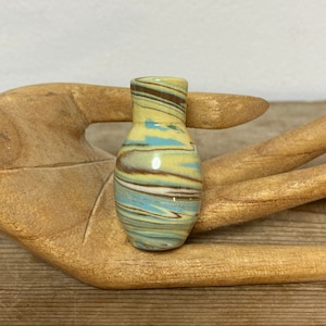 Può includere: Un piccolo vaso in ceramica marmoreggiato di colore giallo, blu e marrone.