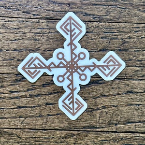 May include: A white sticker with a brown geometric design. The design is a cross with four arms that are made up of a series of connected triangles. The center of the cross has a circle with four smaller circles around it.