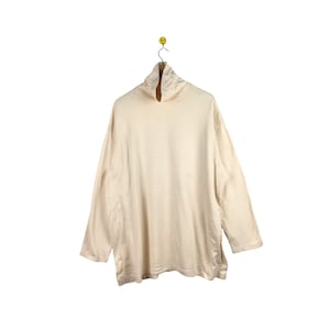 May include: A cream-colored long-sleeved turtleneck shirt.