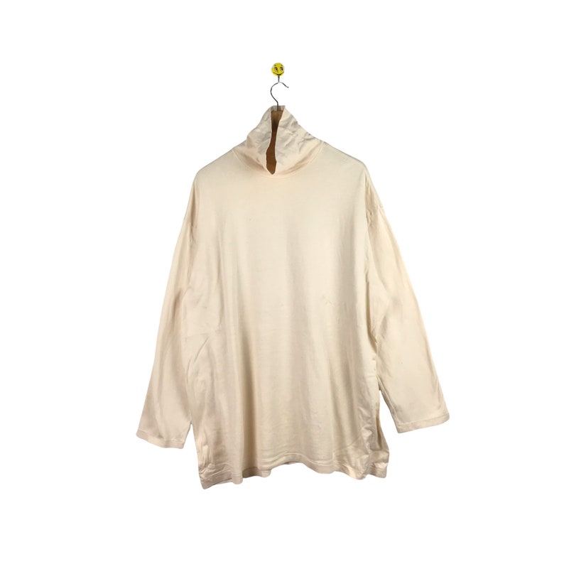 May include: A cream-colored long-sleeved turtleneck shirt.
