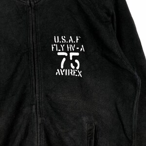 May include: Black zippered sweatshirt with a white print that reads "U.S.A.F. FLY HV-A 75 AVIREX"