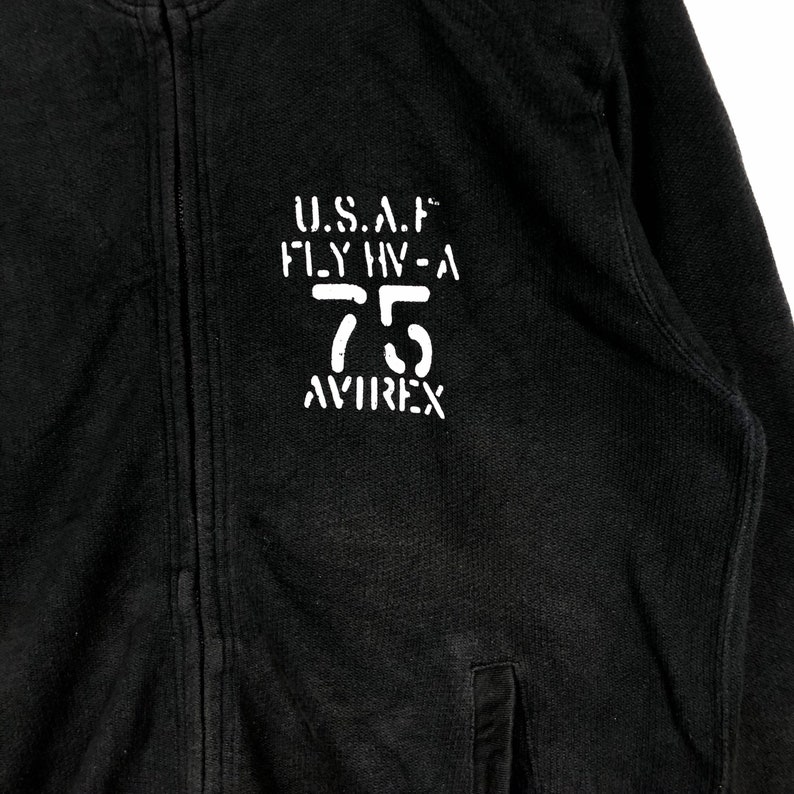May include: Black zippered sweatshirt with a white print that reads "U.S.A.F. FLY HV-A 75 AVIREX"