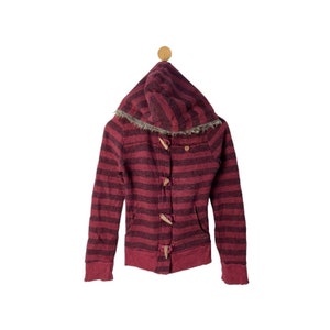 May include: A hooded jacket with a burgundy and black striped pattern. The jacket features wooden toggle closures, a faux fur trim around the hood, and a front pocket. The jacket is hanging on a wooden peg.