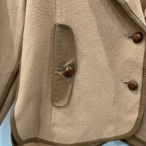 May include: A brown suede jacket with a leather trim and brown leather buttons.