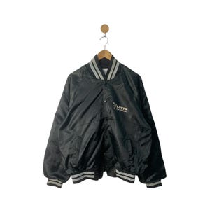 May include: A black satin bomber jacket with white and gray striped ribbing around the collar, cuffs, and hem. The jacket has a button closure and features a Levi's logo embroidered on the chest.