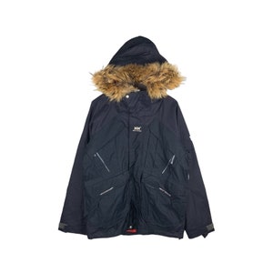 May include: A black hooded winter jacket with a faux fur trim around the hood. The jacket has multiple pockets and the Helly Hansen logo is visible on the chest.