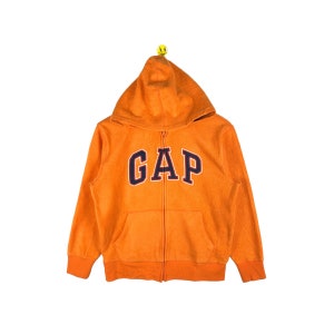 May include: Orange fleece zip-up hoodie with a large navy blue and white "GAP" logo on the front.