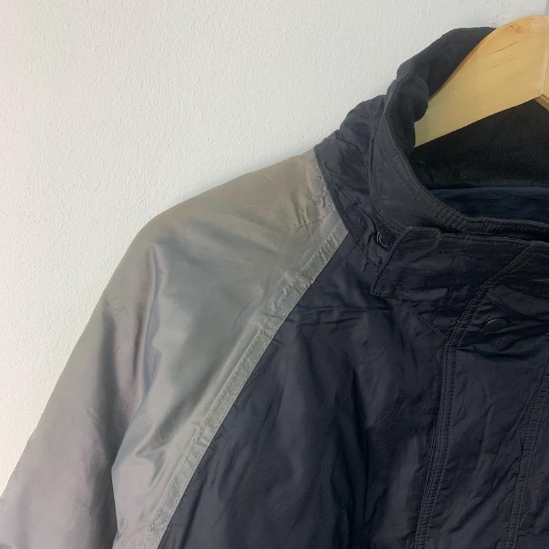 May include: A black and silver jacket with a zipper closure and a hood. The jacket has a reflective silver panel on the left shoulder and arm.