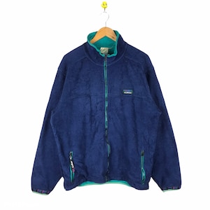Puede incluir: Una chaqueta de forro polar azul marino con una cremallera turquesa y un forro turquesa. La chaqueta tiene un pequeño parche en el pecho con el texto "L.L.Bean" en blanco.