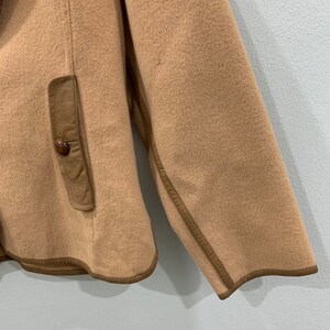 May include: A tan fleece jacket with brown leather trim and a brown leather pocket on the left side.