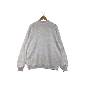 May include: A gray sweatshirt with a crew neck and long sleeves.
