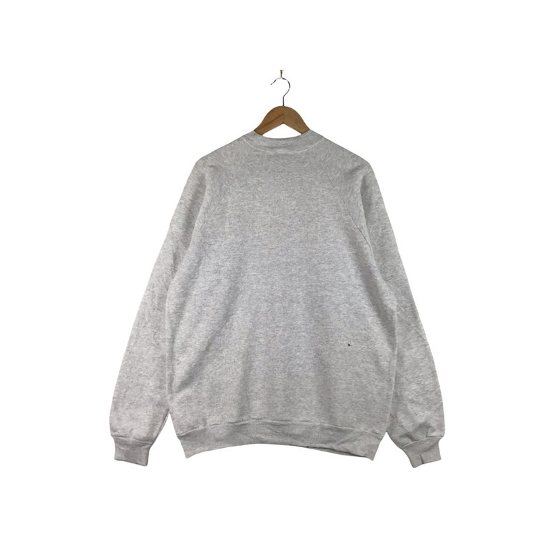 May include: A gray sweatshirt with a crew neck and long sleeves.