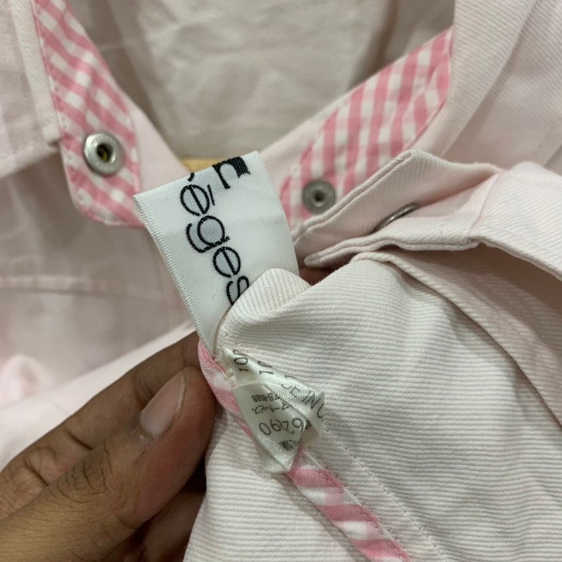 May include: A white denim jacket with pink and white gingham trim. The jacket has a label that says "Edges" on it.