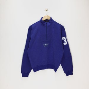May include: A purple quarter-zip sweatshirt with a white "3" on the sleeve and a small embroidered logo on the chest.