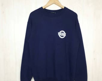 Puede incluir: Una sudadera azul marino con un logotipo blanco de Vans en la parte delantera. El logotipo es un círculo con la palabra "Vans" en su interior.