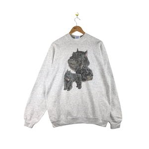 May include: A gray sweatshirt with a graphic print of three black dogs. The dogs are in different poses, with one dog's head facing forward and the other two dogs' heads facing to the side. The sweatshirt has a crew neck and long sleeves.