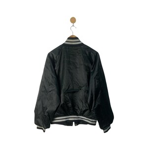 May include: A black satin bomber jacket with white and gray striped trim around the collar, cuffs, and hem.