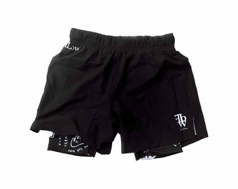 Puede incluir: Shorts de running negros con un logotipo blanco en la pierna derecha y una impresión blanca en la pierna izquierda que dice "Keep the vibe low".