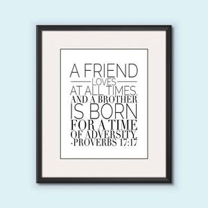 May include: A black and white framed print with a quote about friendship and adversity. The quote reads: "A friend loves at all times, and a brother is born for a time of adversity." -Proverbs 17:17