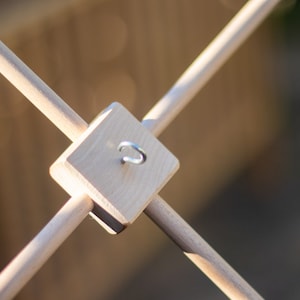 K&ouml;nnte beinhalten: Ein mobiler Holzaufh&auml;nger mit vier D&uuml;beln und einem Haken aus Metall. Der Aufh&auml;nger ist f&uuml;r die Aufnahme eines Mobiles konzipiert.
