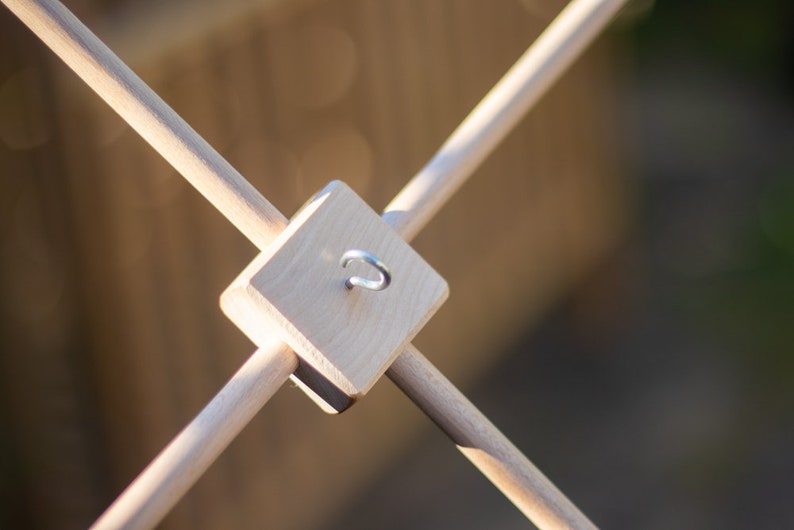 K&ouml;nnte beinhalten: Ein mobiler Holzaufh&auml;nger mit vier D&uuml;beln und einem Haken aus Metall. Der Aufh&auml;nger ist f&uuml;r die Aufnahme eines Mobiles konzipiert.