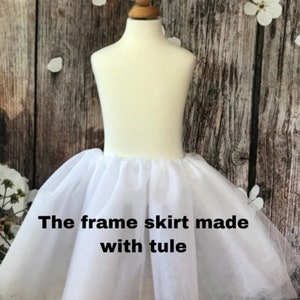 May include: White tulle frame skirt for a dress. The skirt is on a white mannequin. The text "The frame skirt made with tulle" is on the skirt.