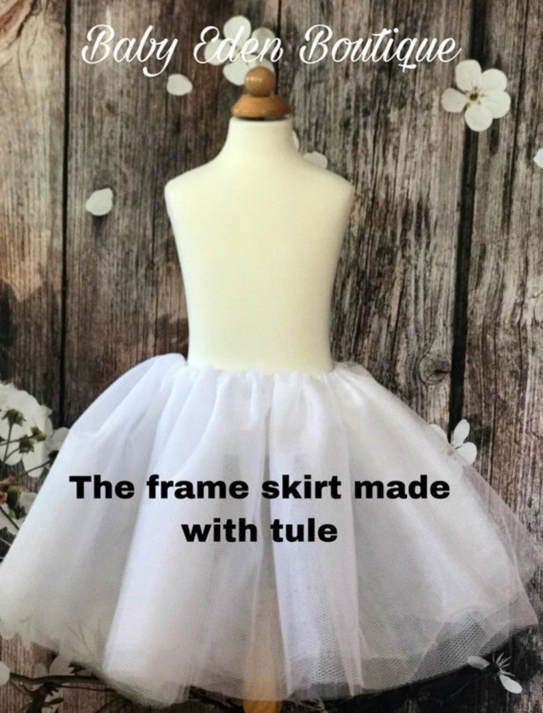 May include: White tulle frame skirt for a dress. The skirt is on a white mannequin. The text "The frame skirt made with tulle" is on the skirt.