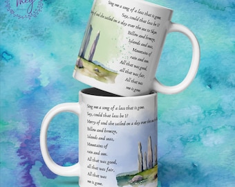 May include: Two white ceramic mugs with a landscape design and text. The design features a watercolor illustration of a coastal scene with standing stones and text from a poem. The mugs have a curved handle.