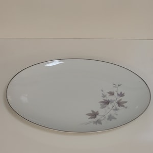 May include: White oval serving platter with a silver rim and a delicate floral design in shades of gray.