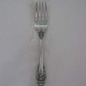 May include: A silver fork with an ornate design and the words "STERLING WALLACE" on the handle.