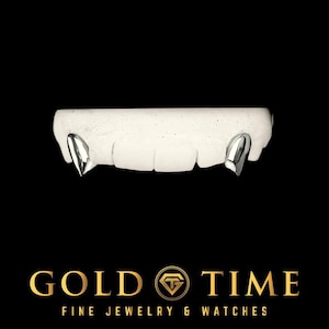 Könnte beinhalten: Silberfarbene, zahnförmige Grillz auf einem weißen Zahnmodell, vor schwarzem Hintergrund. Das Gold Time-Logo mit goldenem Emblem und Text befindet sich unten und wirbt für feinen Schmuck und Uhren.