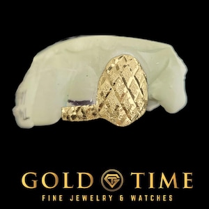 May include: A gold tooth grill with a diamond pattern. The grill is on a white mould.