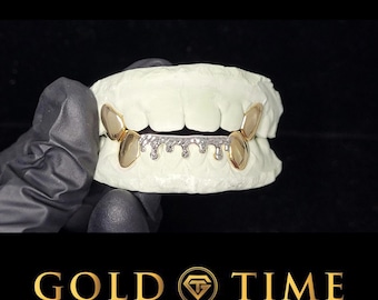 May include: A dental grill set featuring four smooth gold-toned caps on the outer teeth and a central silver-toned piece with a textured, dripping design. The grill is fitted onto a white dental mold, showcasing a metallic finish and distinct shapes.