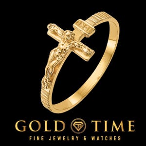 May include: A gold-toned ring with a detailed crucifix design. The ring features a textured band and a raised crucifix with a figure of Jesus Christ.