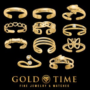 Peut inclure: Une collection de onze bagues ouvertes dorées présentant divers motifs, notamment des cœurs, un dauphin, un papillon et des pierres transparentes. Le texte GOLD TIME FINE JEWELRY & WATCHES apparaît en bas sur un fond noir.