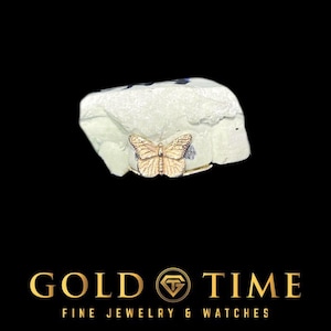 May include: A gold butterfly ring with detailed wing patterns. The ring is presented on a pale green surface against a black backdrop. The words "GOLD TIME" and "FINE JEWELRY & WATCHES" are displayed at the bottom.