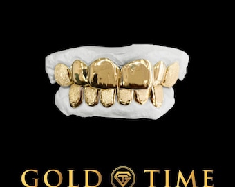 Puede incluir: Un conjunto de fundas dentales de oro con una mezcla de acabados pulidos y texturizados, ajustadas sobre un molde dental blanco. El texto GOLD TIME FINE JEWELRY & WATCHES con un logo en forma de diamante aparece en letras doradas.