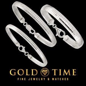 May include: Three silver bracelets with a ribbed design and lobster clasp closures are displayed against a black background. The bracelets are from Gold Time Fine Jewelry & Watches.