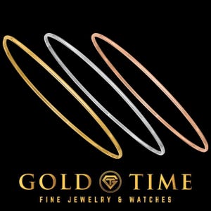 May include: Three thin bangles in gold, silver, and rose gold are displayed against a black background. The gold bangle is on the left, the silver in the middle, and the rose gold on the right. The words "GOLD TIME FINE JEWELRY & WATCHES" are at the bottom.