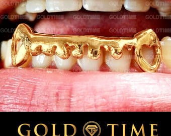 May include: A gold-plated grill with a key design. The grill is worn over the front teeth. The grill is a popular piece of jewelry for hip hop culture.